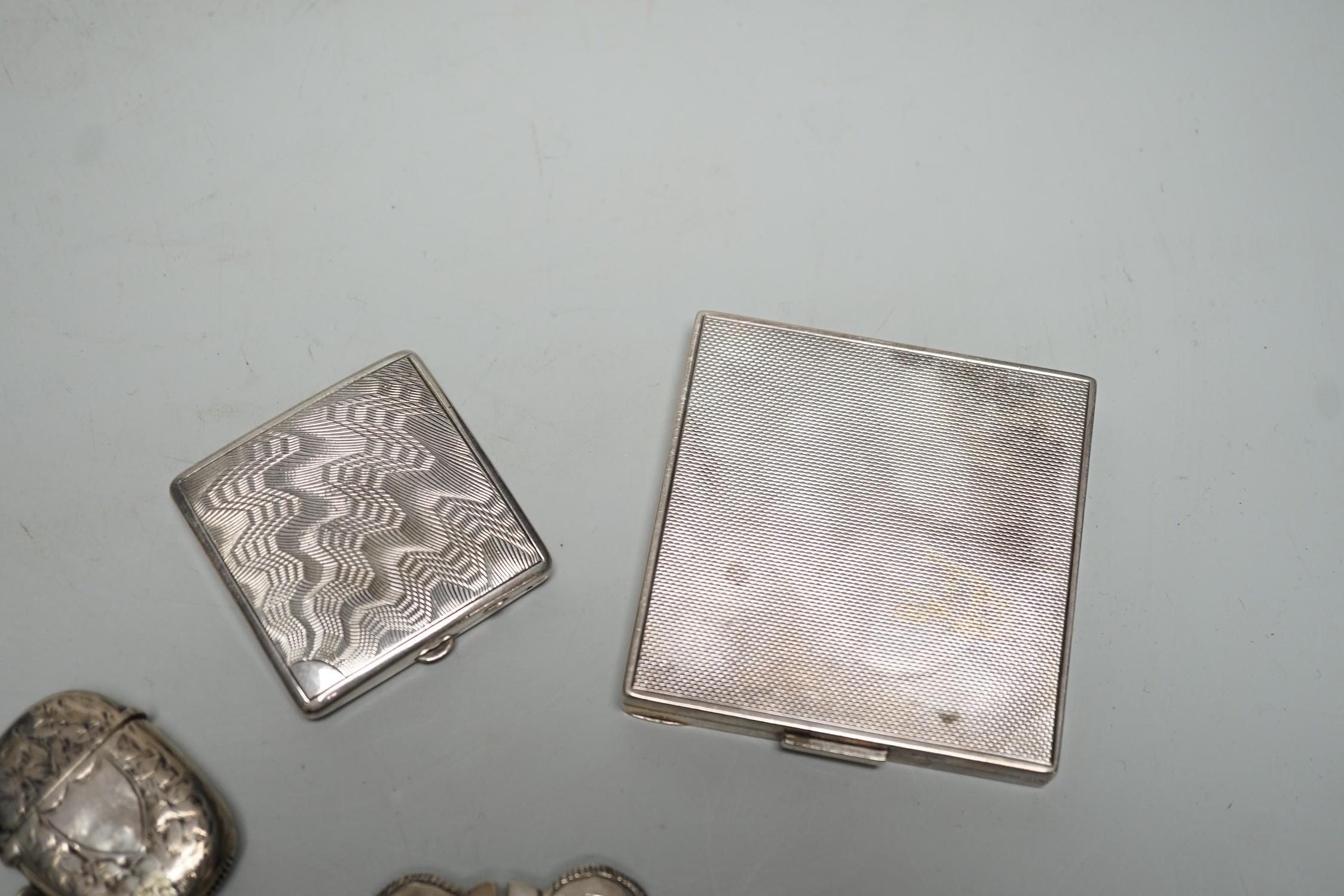 A George VI engine turned silver compact, 69mm, two modern silver pill boxes, a Persian white metal belt buckle, a silver vesta case and a base metal compact.